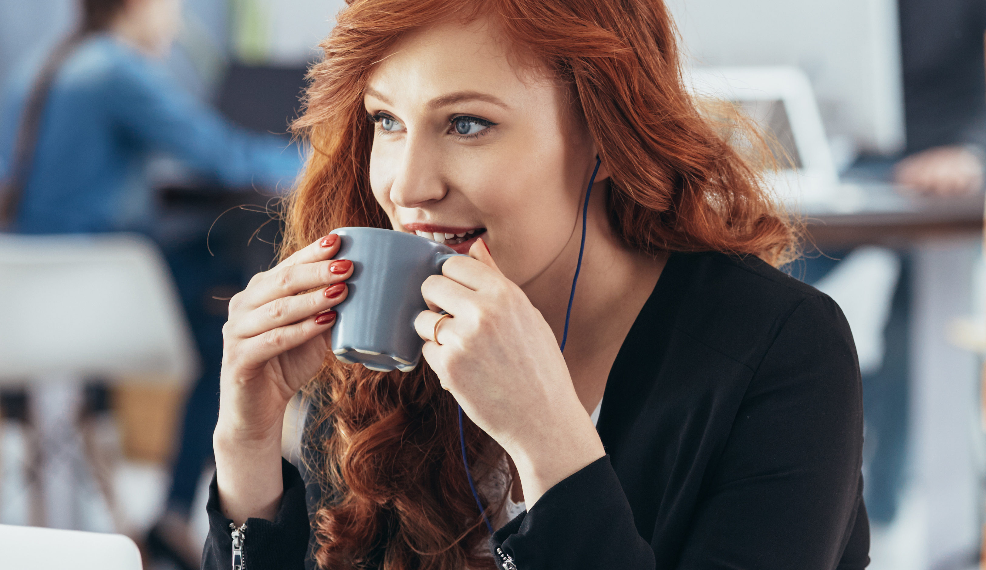 Beautiful young woman drinking coffee in modern office
